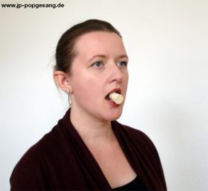 Turbo Tipps Üben Nr. 12 Die Korken Methode Auf dem Foto siehst du eine Frau, die einen Korken zwischen den Zähnen hält.