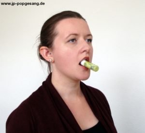 Turbo Tipps Üben Nr. 12 Die Korken Methode Auf dem Foto siehst du eine Frau, die einen Lippenpflegestift zwischen den Zähnen hält.