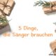 5 Dinge, die Sänger brauchen Das Bild zeigt 5 Geschenke in goldenem Papier mit Tannenzweigen dekoriert.