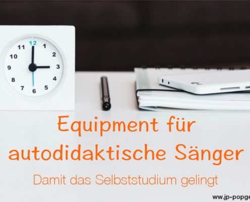 Equipment für autodidaktische Sänger Das Foto zeigt eine weiße Uhr, einen Stift, ein weißes Notizbuch und ein weißes Mobiltelefon, das auf einem weißen Tisch vor dunklem Hintergrund liegen.
