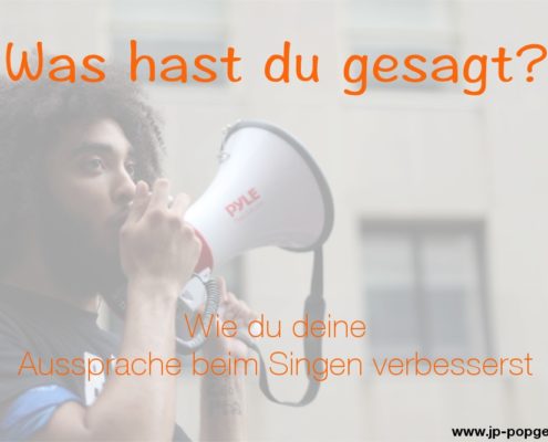 Aussprache beim Singen Das Foto zeigt einen schwarzen jungen Mann mit einem Megaphon vor einem Haus.