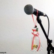Geschenkideen für giggende Sänger Das Foto zeigt ein Mikrofon mit Weihnachtsdekoration vor einer weißen Wand.