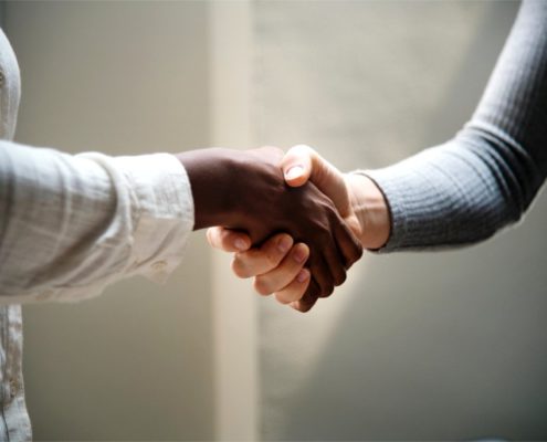 Probestunde im Gesangsunterricht Das Foto zeigt zwei Menschen, die sich zur Begrüßung die Hände schütteln.
